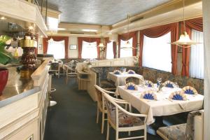 un restaurante con mesas y sillas blancas y ventanas en Blaue Grotte & Frankenhotel en Debring