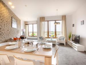 jadalnia ze stołem i krzesłami oraz salon w obiekcie VacationClub – Olympic Park Apartament B601 w Kołobrzegu