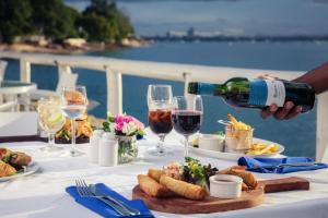 Coral Beach Hotel Dar Es Salaam في دار السلام: شخص يصب كأس من النبيذ على طاولة مع الطعام