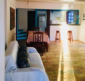 a living room with a couch and a kitchen with a table at Casas Coloniais in Morro de São Paulo