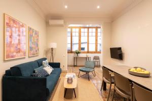 Aspasios Gracia Apartments في برشلونة: غرفة معيشة مع أريكة زرقاء وطاولة