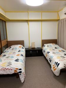 2 Betten nebeneinander in einem Zimmer in der Unterkunft 海天house in Beppu