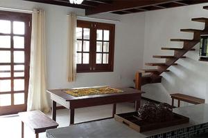 ein Wohnzimmer mit einem Tisch und einer Treppe in der Unterkunft Casas Coloniais in Morro de São Paulo