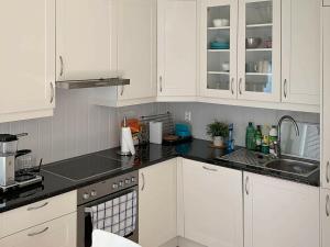una cucina con armadietti bianchi e ripiani neri di 6 person holiday home in ETNE a Etnesjøen