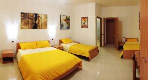 two beds in a room with yellow sheets at B&B Casa La Dolce Vita in Nuova Gibellina