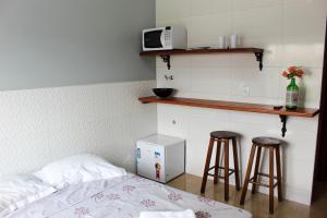 1 dormitorio con 1 cama, 2 taburetes y microondas en Disponivel Virada - Estúdios e suítes com piscina, ar, wifi e estacionamento 6X no cartão sem juros, en Porto Belo