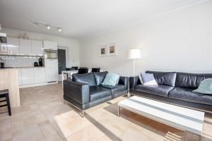 ein Wohnzimmer mit einem Sofa und einem Tisch in der Unterkunft Strandvakantieappartement Zilverstrand - met binnenzwembad! in De Haan