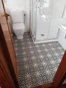 a bathroom with a toilet and a tile floor at La Corte del Rondiellu 1 in Bobia de Abajo