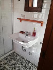 La salle de bains est pourvue d'un lavabo blanc et d'une douche. dans l'établissement La Corte del Rondiellu 1, à Bobia de Abajo