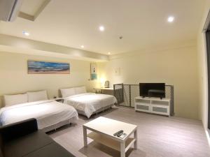 a hotel room with two beds and a flat screen tv at In Fengchia in Taichung