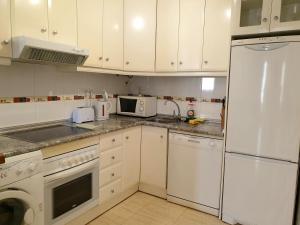 a kitchen with white cabinets and a white refrigerator at Studio Parque Mar in La Mata