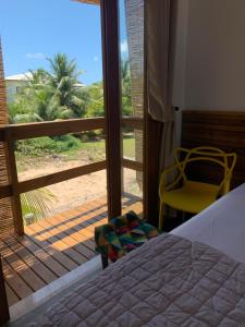 a bedroom with a bed and a view of a balcony at Raios de Sol Ville - Taipu de Fora in Barra Grande