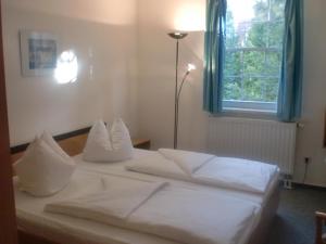 ein weißes Bett in einem Zimmer mit Fenster in der Unterkunft Hotel & Restaurant "Zum Firstenstein" in Königshain
