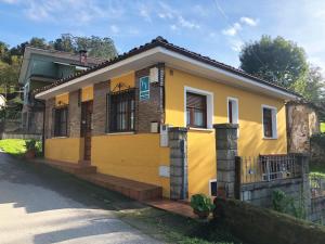ein gelbes Haus mit einem Zaun davor in der Unterkunft Casa Valle in Cangas de Onís
