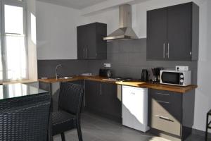 a kitchen with black cabinets and a microwave at Appart's Village Trama Loges in Puymirol