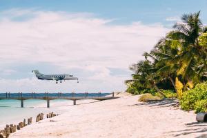 ein Flugzeug, das über einen Strand mit einer Brücke fliegt in der Unterkunft Four Seasons Resort Seychelles at Desroches Island in Desroches