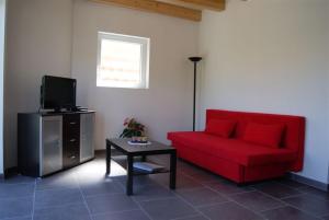 uma sala de estar com um sofá vermelho e uma televisão em Gîte Binnert Bader em Nothalten