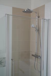 prysznic ze szklanymi drzwiami i głowicą prysznicową w obiekcie Maison Latour w mieście Cholet