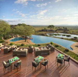 een patio met tafels en stoelen naast een zwembad bij Four Seasons Safari Lodge Serengeti in Banagi