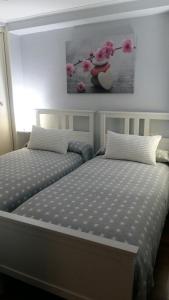 a bedroom with two beds and a painting on the wall at Apartamento en Caión in A Coruña