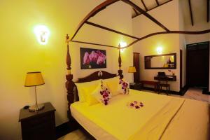 a bedroom with a large bed with yellow walls at SRI LANKAN VILLA in Galle