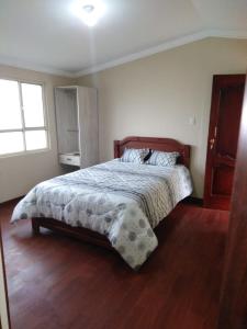 a bedroom with a bed with a wooden floor at HOSPEDAJE CARIGAN in Loja