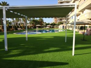 a pavilion at a resort with a swimming pool at Apartamento 1ª Línea de mar en Marina d'Or con césped y playa [Familiar] in Cabanes +18 photos