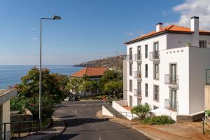 una strada vuota con un edificio bianco e l'oceano di Apartamento Lobo Marinho by An Island Apart a Santa Cruz