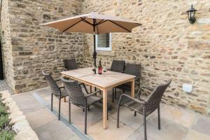 a wooden table with chairs and an umbrella at Hayloft Cottage in Durham