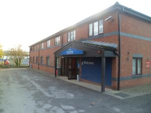 a red brick building with a blue sign on it at Metro Inns Huddersfield in Huddersfield