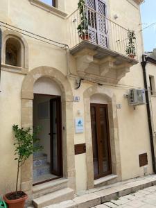 a building with a balcony and two doors and a plant at alex rooms in Ragusa