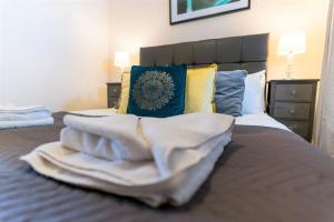einen Stapel Handtücher auf dem Bett in der Unterkunft Wordsworth Apartment Irene court in Cockermouth