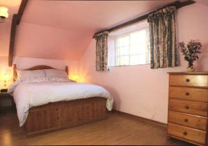 1 dormitorio con cama, ventana y vestidor en Old Newham Farm, en Camelford