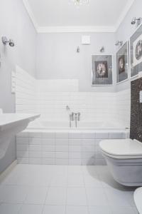 a white bathroom with a tub and a toilet at Saskasummer in Warsaw