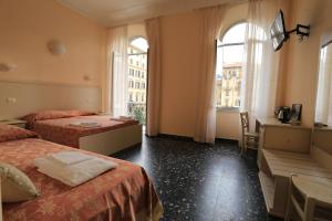a hotel room with two beds and a desk and two windows at Vivi 5 terre in La Spezia +100 photos