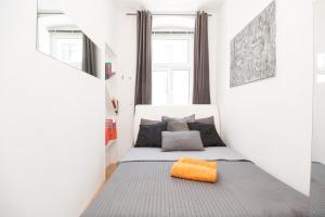 ウィーンにあるVienna-Design-Apartmentsの小さなベッドルーム(オレンジ色の枕付きのベッド付)