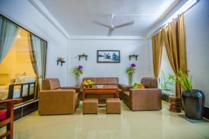 uma sala de estar com um sofá, cadeiras e uma mesa em Moloppor Villa em Battambang