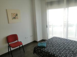 アルカンタリージャにあるApartamento Príncipeのベッドルーム1室(ベッド1台、赤い椅子付)
