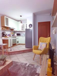 un salon avec une chaise jaune et une cuisine dans l'établissement The House At The Pines, à Péfka