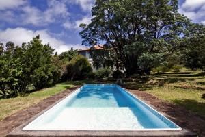 a swimming pool in the yard of a house at Quinta das Colmeias in Santo António da Serra