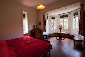 a bedroom with a bed and a table and windows at Quinta das Colmeias in Santo António da Serra