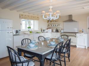 a kitchen with a table with chairs and a chandelier at Penrhyn Barn in Penrhos-Lligwy
