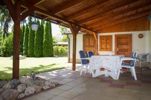 eine Terrasse mit einem Tisch und Stühlen unter einem Holzdach in der Unterkunft Familia Nyaraló 3 in Balatonmáriafürdő