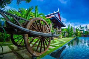 a wooden bench sitting next to a pool of water at Moloppor Villa in Battambang