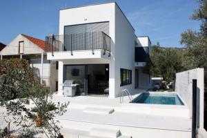 a white house with a swimming pool in front of it at Domo Oliveto in Vinišće