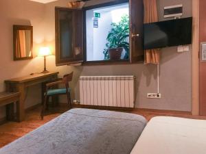 um quarto com uma cama, uma secretária e uma janela em Hotel Fonda Merce em Llivia