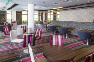 a restaurant with tables and chairs and a bar at Holiday Inn Express London - Epsom Downs, an IHG Hotel in Epsom
