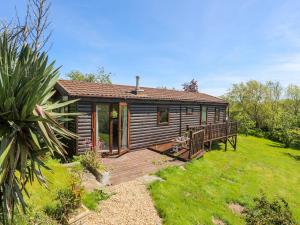 a log cabin with a wooden deck in a yard at Castell Chalet in Pwllheli