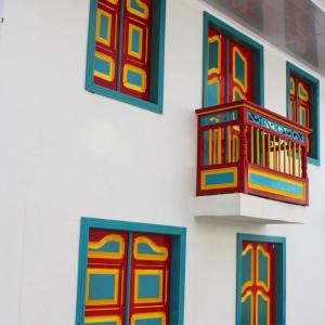 a white wall with colorful windows on it at Casa Pachamama in Salento