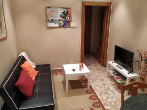 een woonkamer met een bank, een tafel en een tv bij APARTAMENTO CENTRO GIJON Vut1703AS in Gijón